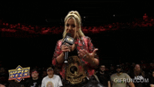 a woman speaking into a microphone in front of a crowd with a gifrun.com logo in the background