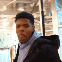 a man wearing a purple hoodie and a black jacket is making a face
