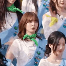 a girl wearing a green scarf around her neck has the letter r on her shirt .