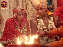 a bride and groom are standing in front of a fire with a dangal tv logo behind them