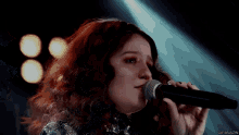a close up of a woman singing into a microphone with gifsbiazin in the corner