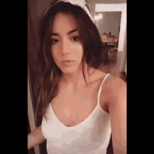 the woman is wearing a white tank top and a headband .