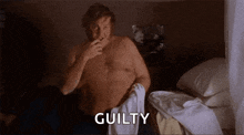 a shirtless man is sitting on a bed holding a towel and saying guilty .
