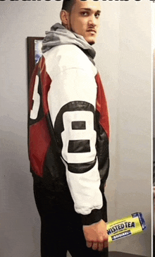 a man wearing a number 8 jacket is holding a twisted tea packet