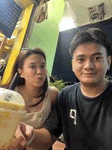 a man and a woman are posing for a picture and the man is wearing a black shirt with the letter s on it