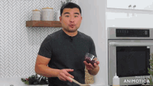a man in a black shirt is holding a glass and a wooden spoon in front of a made in animatica oven