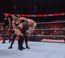 two women are wrestling in a wrestling ring with a crowd in the stands watching
