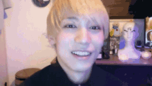 a man with blonde hair is smiling in front of a mannequin head with the letter h on it