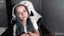 a girl with blue hair is wearing headphones and sitting in a white chair