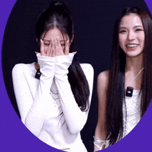 a woman covering her face with her hands while another woman smiles behind her
