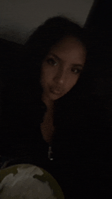 a woman is holding a plate of food in her hand in the dark .