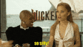 two women are sitting in front of a sign that says wicked on it