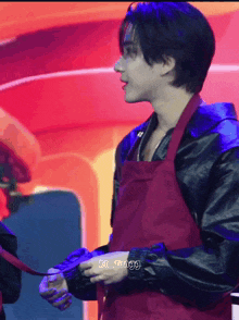 a man wearing a red apron and a black jacket has the name ki_tung9 on his arm