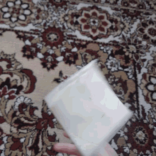 a person is holding a piece of paper in front of a patterned rug