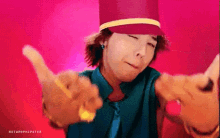 a man wearing a red hat and a blue shirt is giving a thumbs up sign .