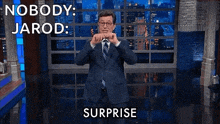 a man in a suit and tie is standing on a stage with his arms outstretched and says nobody jarod surprise
