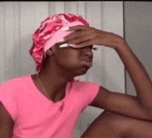 a woman wearing a pink shirt and a pink hat is covering her face .