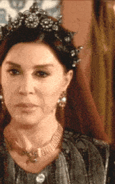 a close up of a woman wearing a necklace and a tiara .