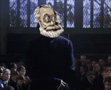 a man with a beard and goggles is standing in front of a group of people .