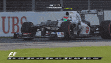 a race car is on a track with a ubs sign in the background