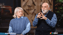 a man and a woman are sitting in front of a sign that says nbc on it