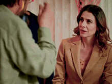 a man in a green shirt talks to a woman in a tan suit