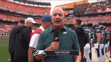 a man in a green eagles shirt is holding a microphone