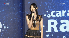 a woman is holding a microphone in front of a screen that says live