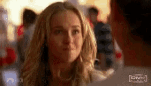 a woman with blonde hair is looking at a man in a crowd .