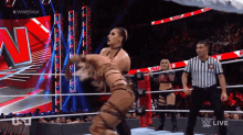 two women are wrestling in a wrestling ring while a referee looks on ..