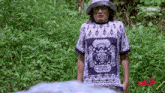 a man wearing a hat and a blue and white shirt is standing in the grass with astro channel written on the bottom