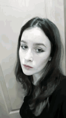 a girl with long dark hair and a nose ring looks at the camera