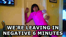 a woman in a pink outfit is holding a baby and says " we 're leaving in negative 6 minutes "