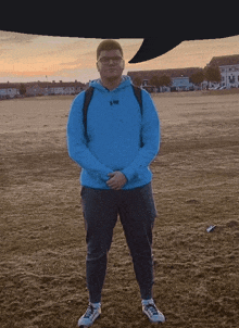 a man wearing a blue hoodie that says army stands in a field