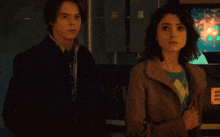 a man and a woman are standing next to each other and looking at the camera