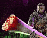 a man in a hood is holding a large sword with blood on it .