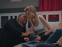a man and woman are kissing on a bed with a pink curtain behind them