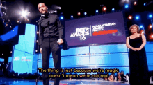 a man stands in front of a large screen that says beta awards