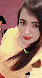 a woman in a yellow shirt is taking a selfie with her phone .