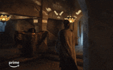 a man in a gray cape stands in a dark room