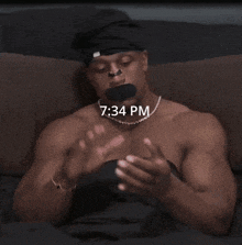 a shirtless man laying on a bed with the time 7:34 pm
