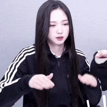 a woman with long black hair wearing a black adidas jacket