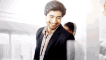 a man in a suit and tie is smiling in a blurry photo