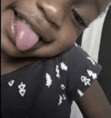 a little girl sticking her tongue out while wearing a black shirt
