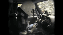 a man wearing a white helmet is driving a car