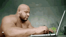 a shirtless man is typing on a laptop while eating a salad .