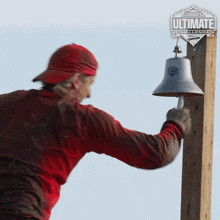 a man in a red shirt is ringing a bell with a canada ultimate challenge logo in the background