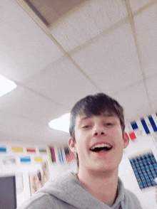 a young man is smiling in a room with flags on the wall behind him