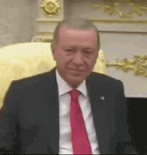 a man in a suit and tie is sitting in a chair in front of a fireplace .