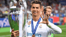a soccer player holding a trophy with a medal around his neck that says emirates